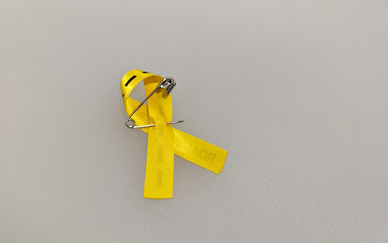 Safety pin secured to back of yellow ribbon