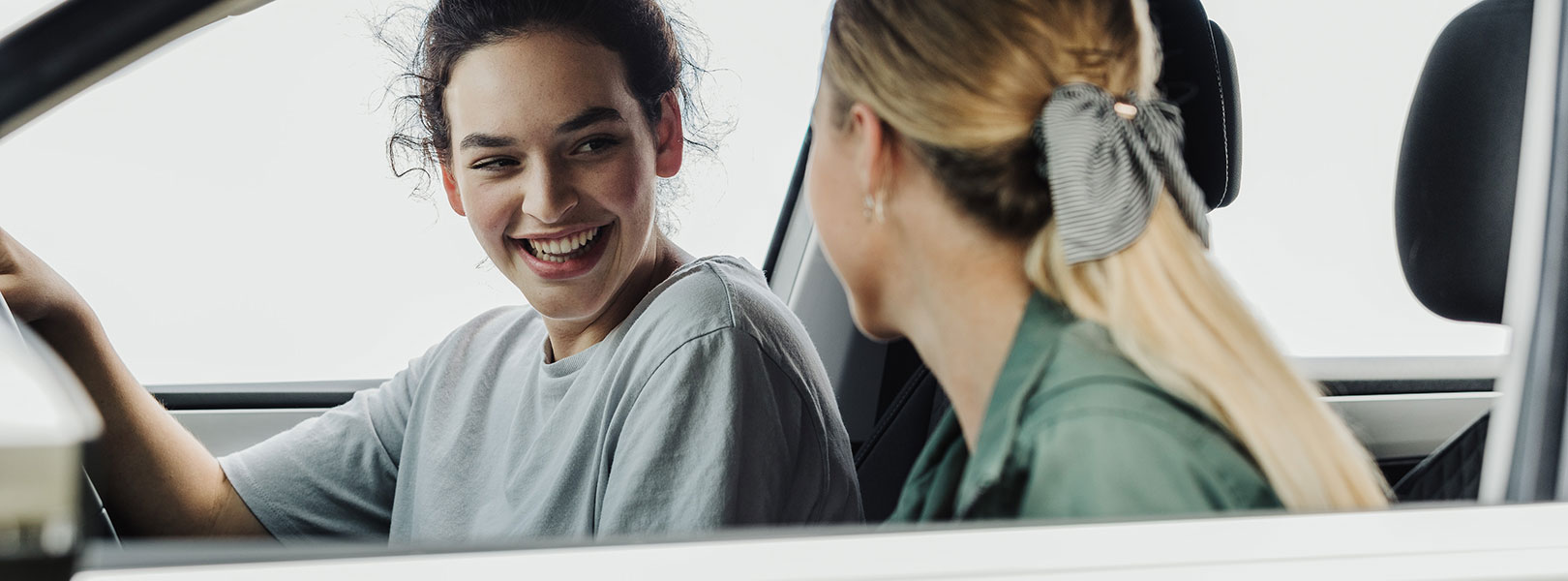 Young girls in car chatting and laughing whilst parked.