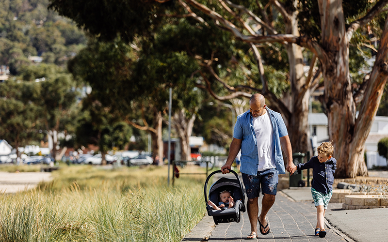 Dad walking along beach path with two young children