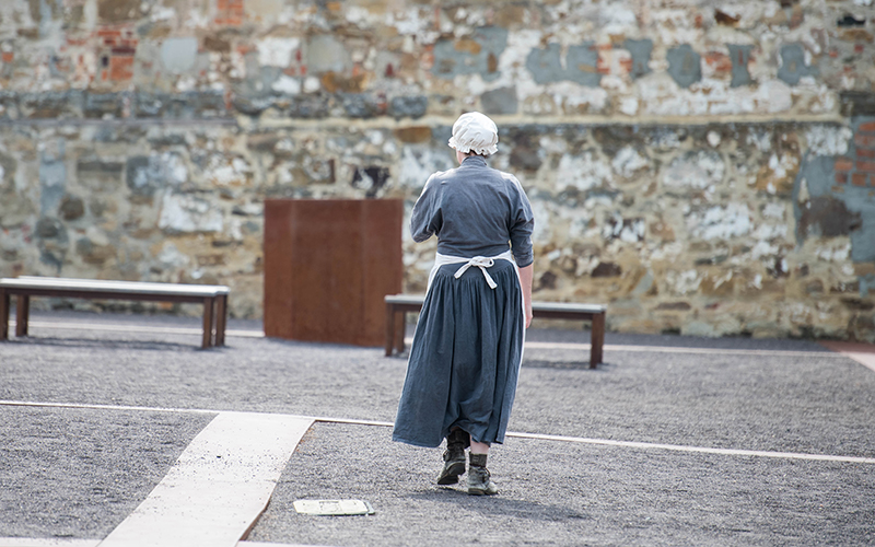 Woman in convict uniform walking in convict ruins