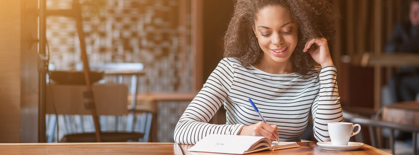 Lady sitting in cafe writing in journal
