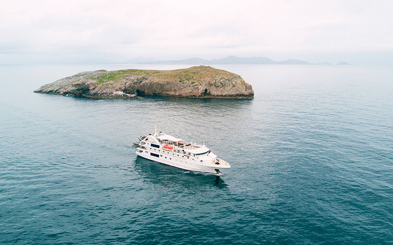 The Coral Discoverer cruising next to a small island off the coast of Tasmania