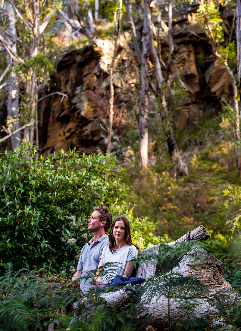 Couple relaxing on rock in front of cave