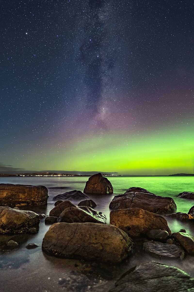 Green and purple aurora over the beach