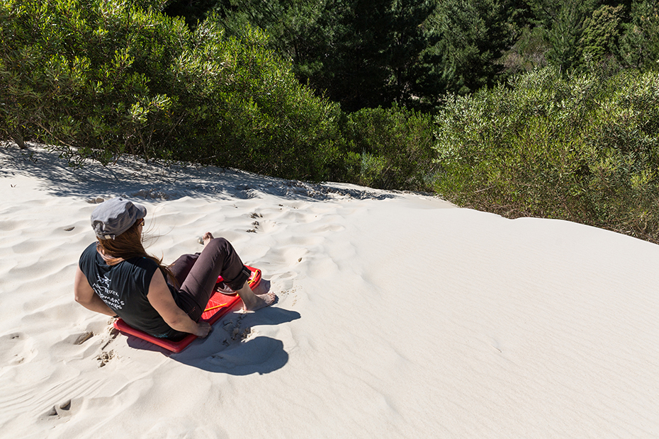 Tobogganing down Henty Dunes in Tasmania
