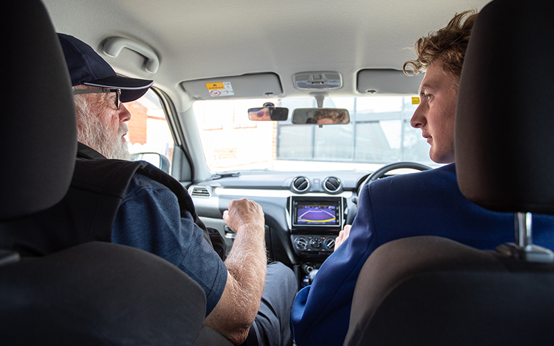 Learner driver and driver educator in car.