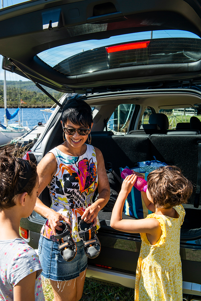 Mum unpacking kids' shoes from the boot of a car