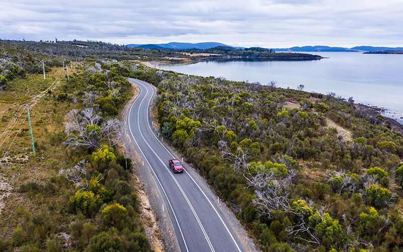 Ariel view of red Mazda BT-50 driving down coastal road