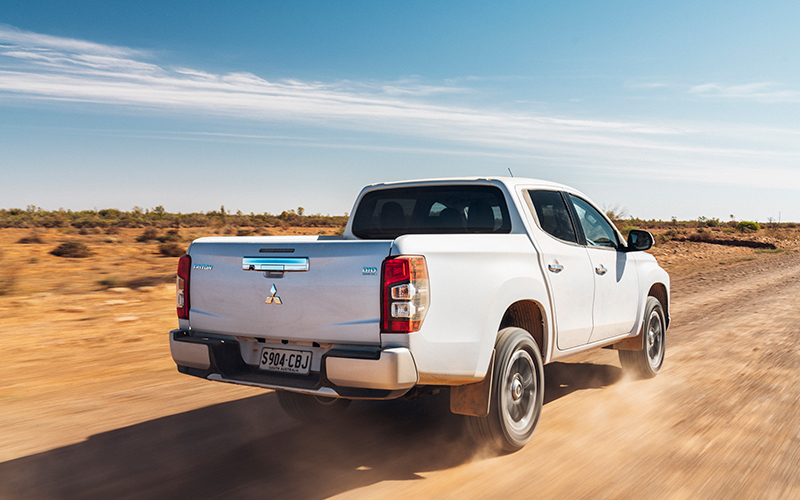 White Mitsubishi Triton driving on dirt road