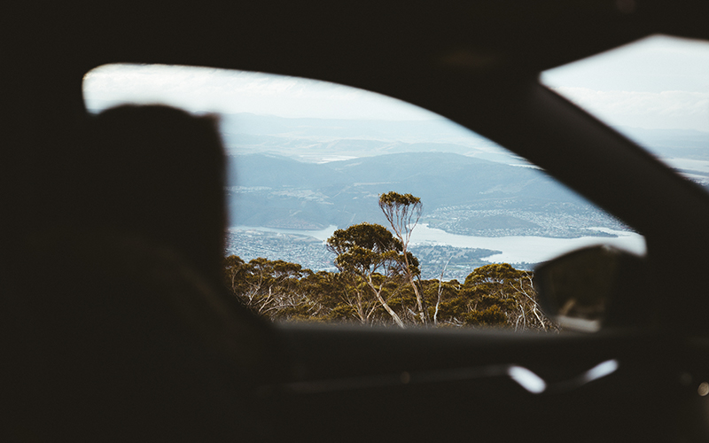 Woman driving car on Mt Wellington with view in background