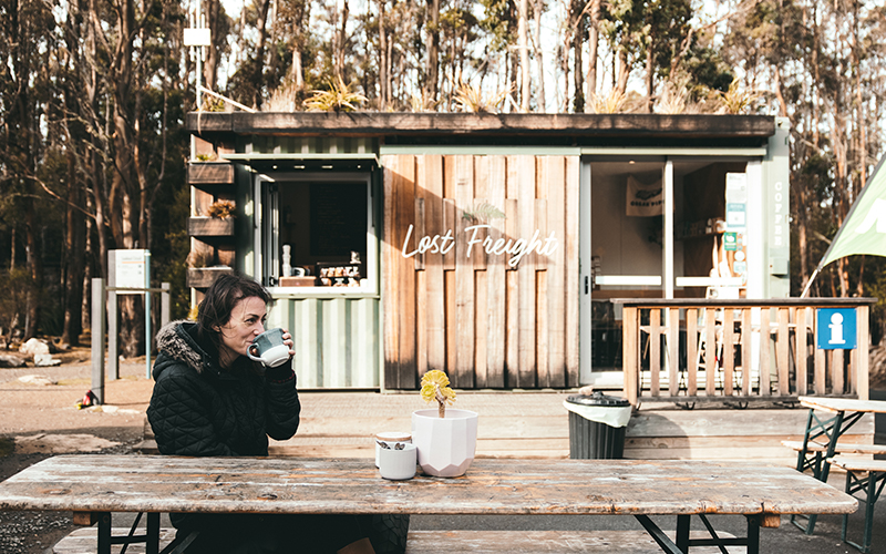 Woman drinking a coffee outside Lost Freight at the Mount Wellington Springs
