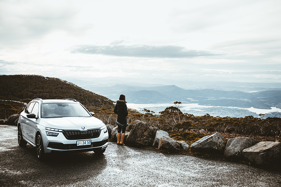 Woman admiring the view with the Skoda Kamiq on top of Mount Wellington