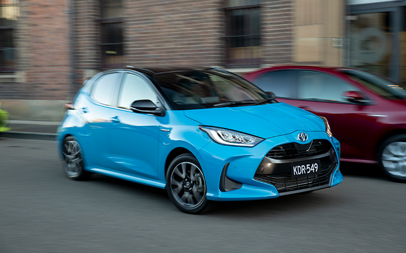 Blue Toyota Yaris Hybrid driving through city streets