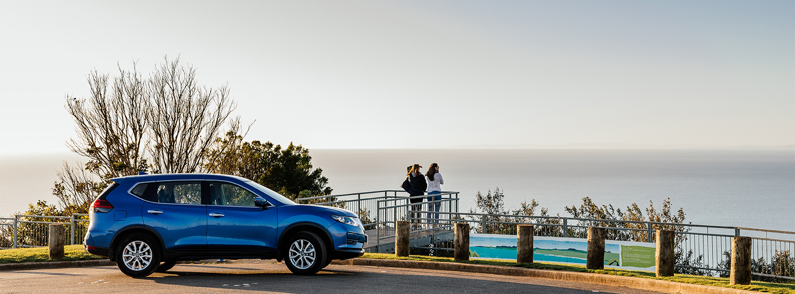 Two ladies looking out to sea from a look out parking area.