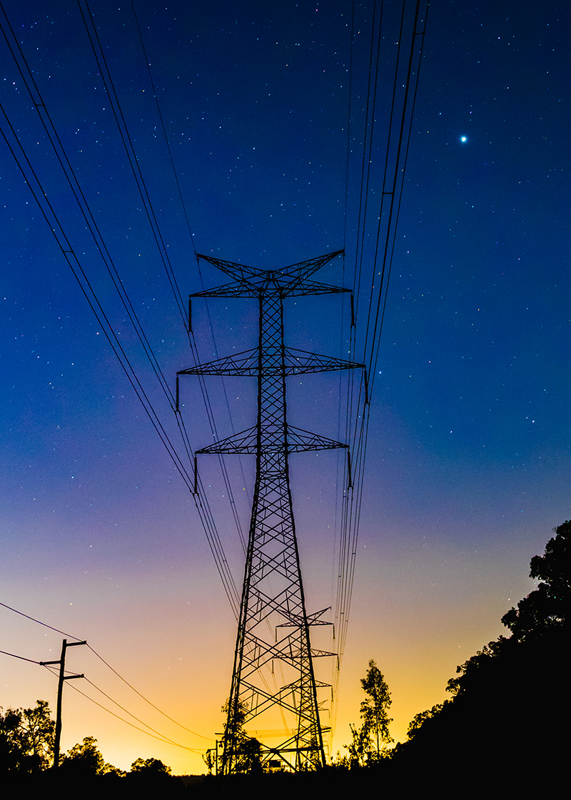 Silhouette of powerlines against blue and yellow sunset