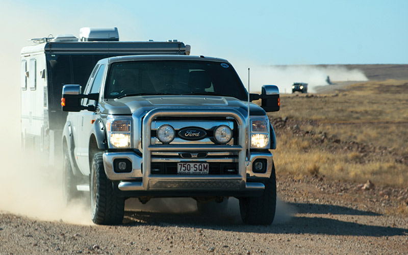 Car driving with caravan attached in the outback.