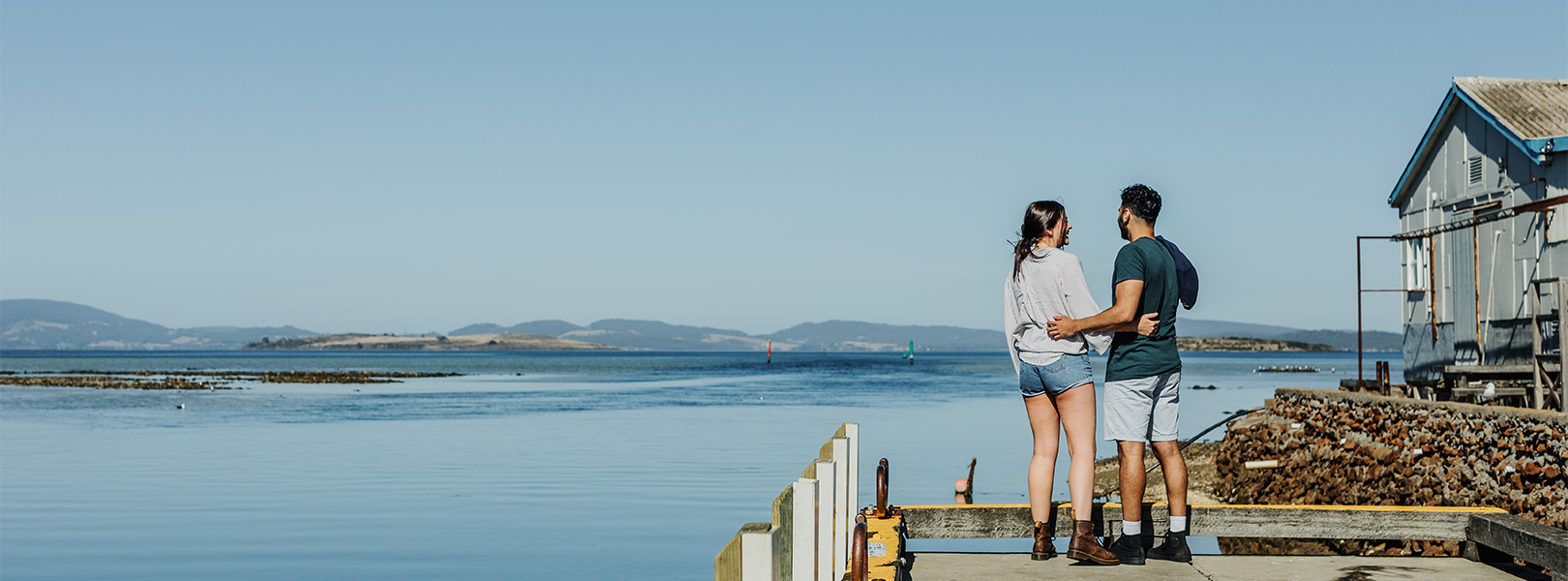 Couple looking over sea from wharf