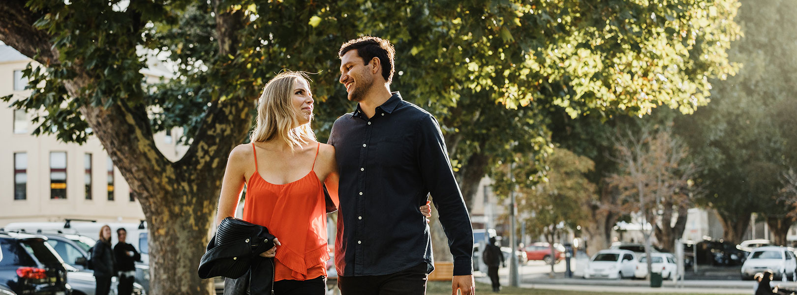 Couple walking through park romantically with sun in background