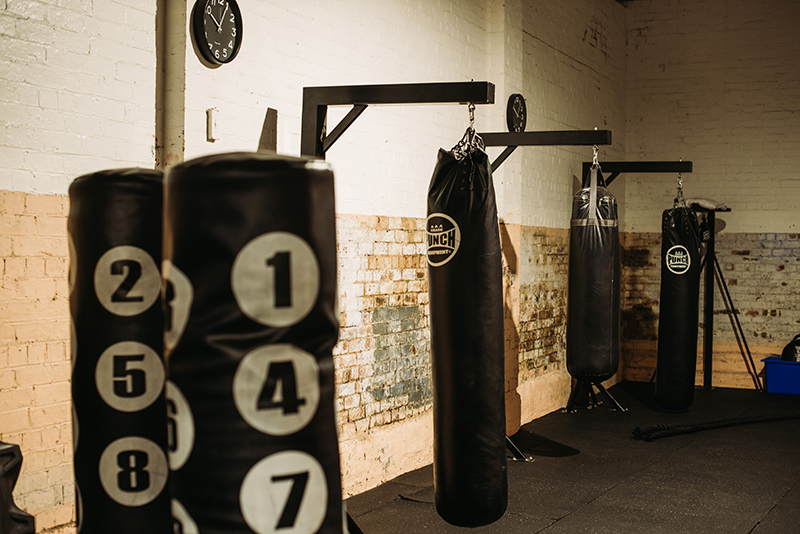 Cross fit training area with painted brick walls and old school punching bags.