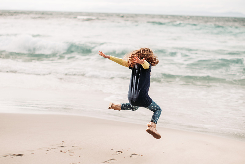 Child jumping for joy at Neck Beach, Bruny Island.