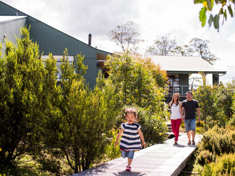 Child running down the path with parents following behind at Cradle Mountain Lodge.