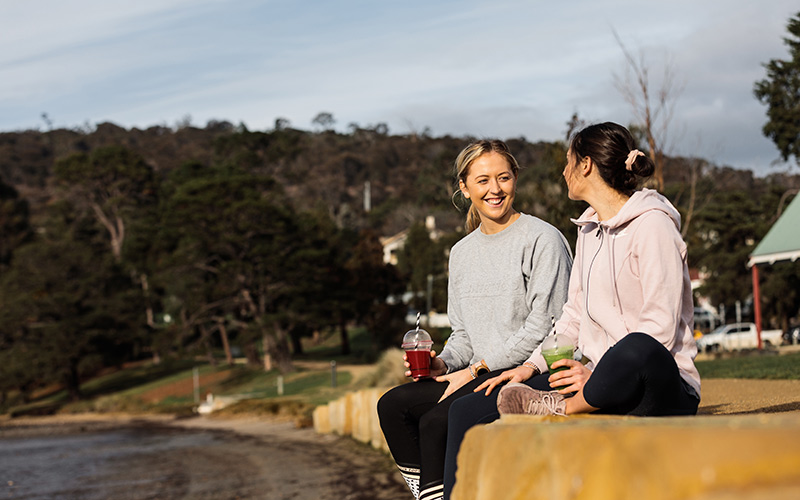 Girls sitting on beach with smoothies